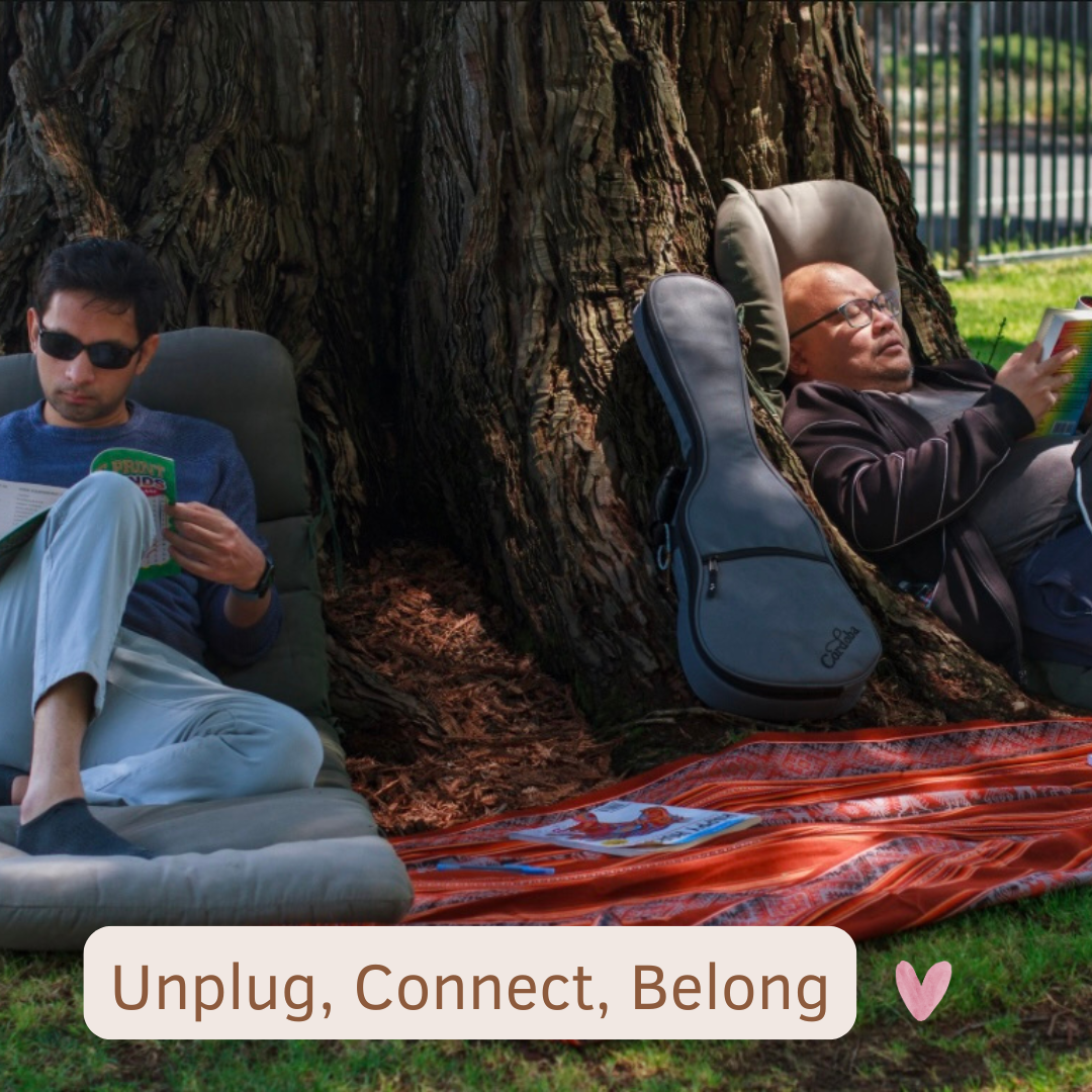 Two community members reading quietly under a large tree