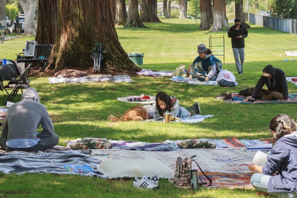 Group gathered on picnic blankets under the trees